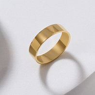 Yellow gold polished wedding band on a light background.