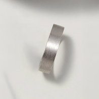 Brushed white gold wedding band on a light background.