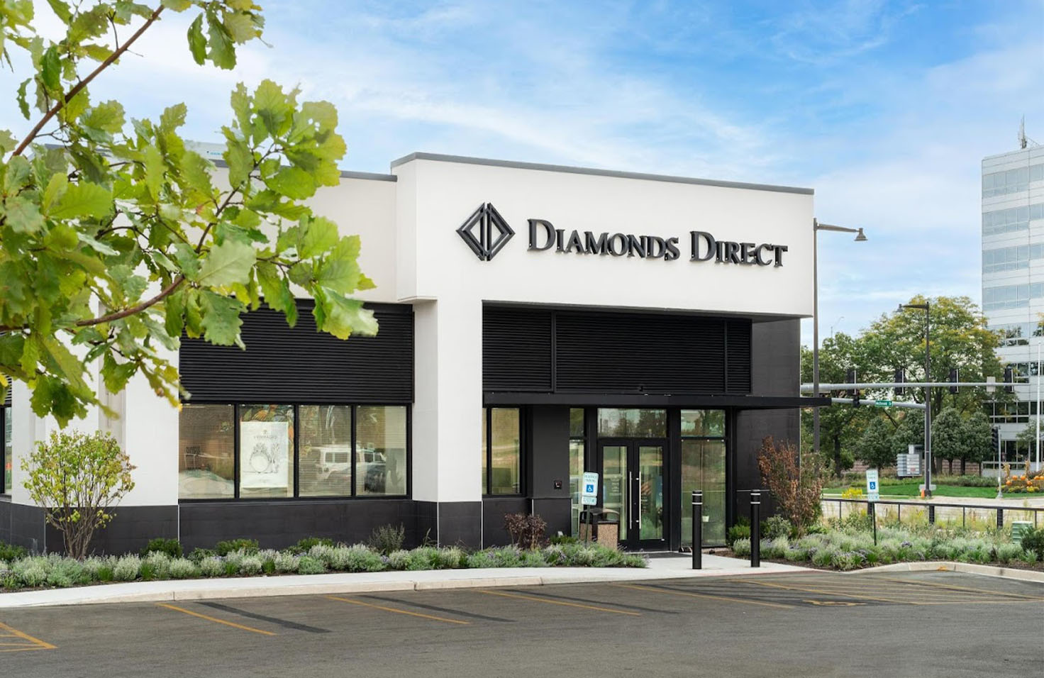 Diamonds Direct Diamonds Direct jewelry store exterior with modern white facade, black accents, and landscaped entrance.