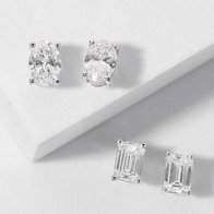 {"en-us":""} {"en-us":"Diamond stud earrings in round and emerald‑cut settings displayed on a white surface."}