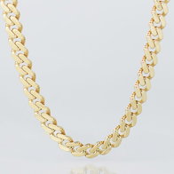 Yellow gold curb chain necklace close‑up on neutral background.