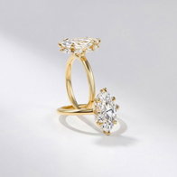 Two marquise-cut hidden-halo diamond engagement rings with yellow gold bands displayed on a light background.