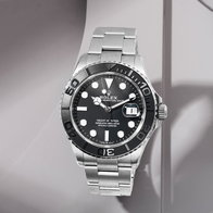 Stainless steel dive watch with black dial and black bezel on a light background.